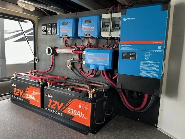 Two lithium batteries with an inverter and solar charging equipment in an RV compartment
