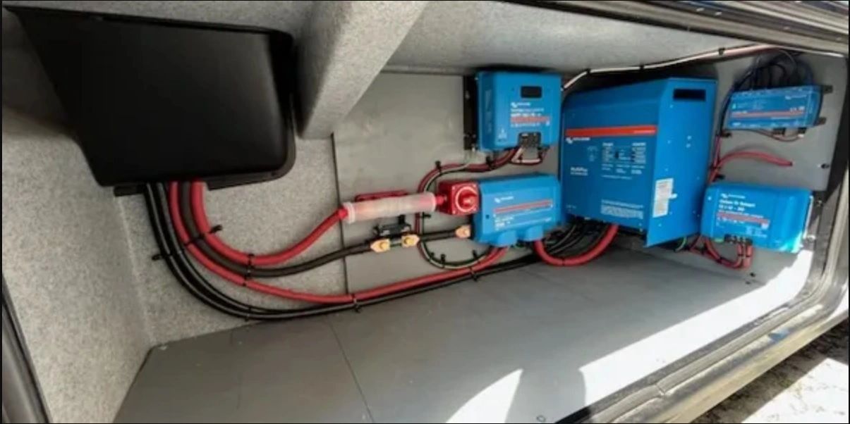RV electrical compartment with installed inverter, solar controllers, and power distribution equipment