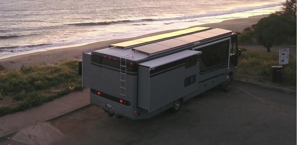 Motorhome with rooftop solar panels overlooking the coast at sunset